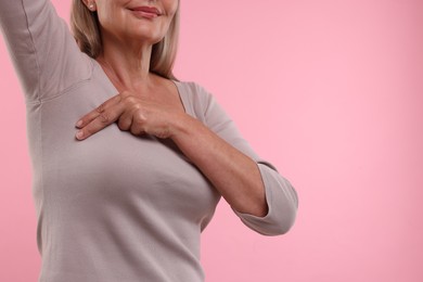 Photo of Woman doing breast self-examination on pink background, closeup. Space for text