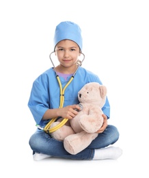 Cute child playing doctor with stuffed toy on white background