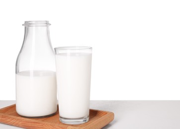 Glassware with tasty milk on light table against white background