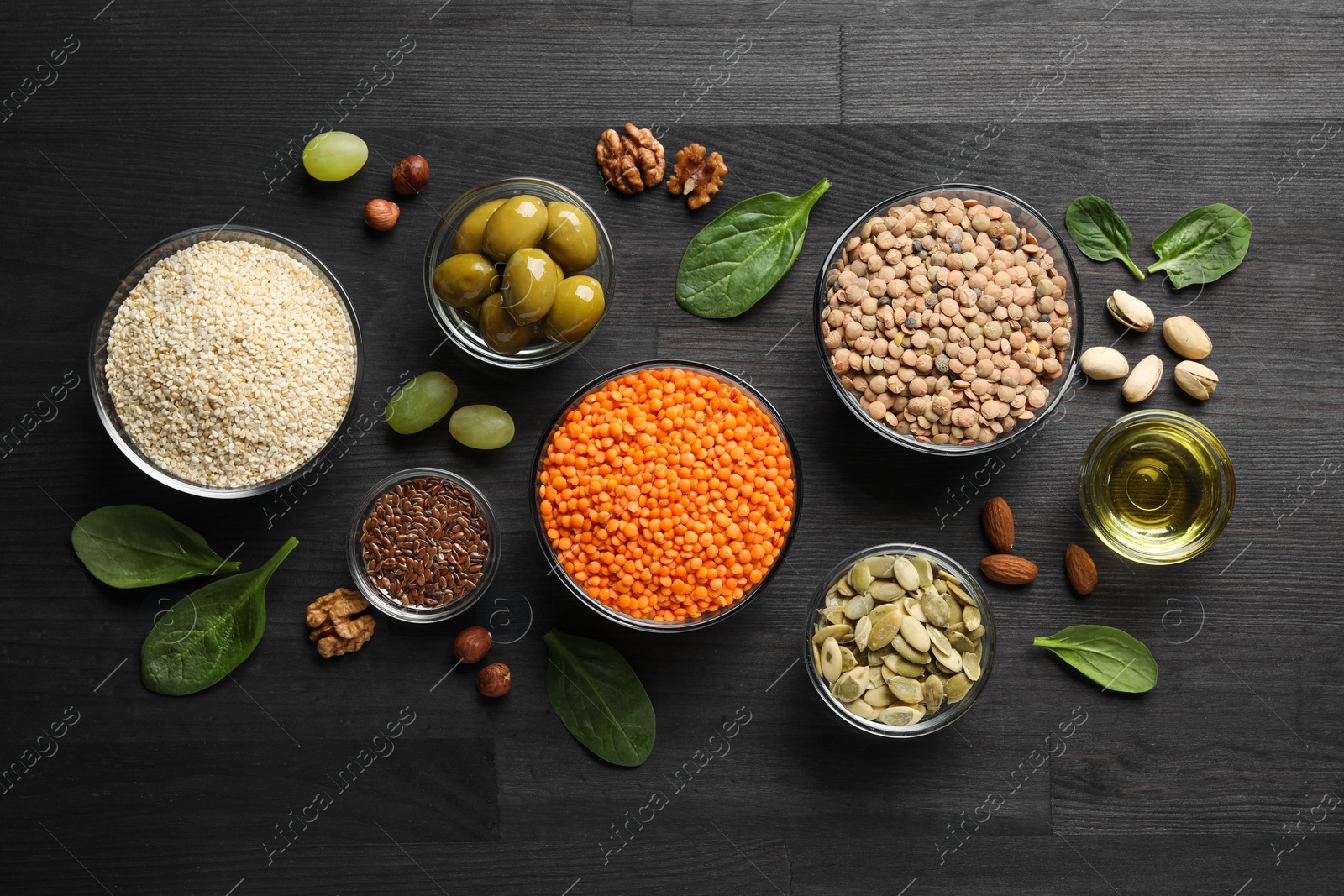 Photo of Different products high in healthy fats on black wooden table, flat lay