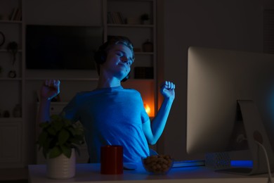 Photo of Teenage boy using computer in bedroom at night. Internet addiction
