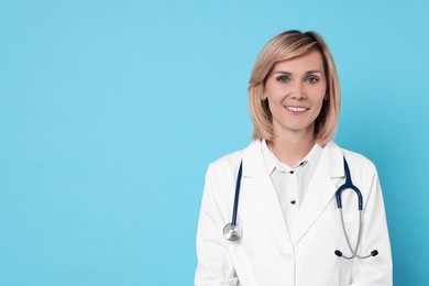 Photo of Smiling doctor on light blue background. Space for text