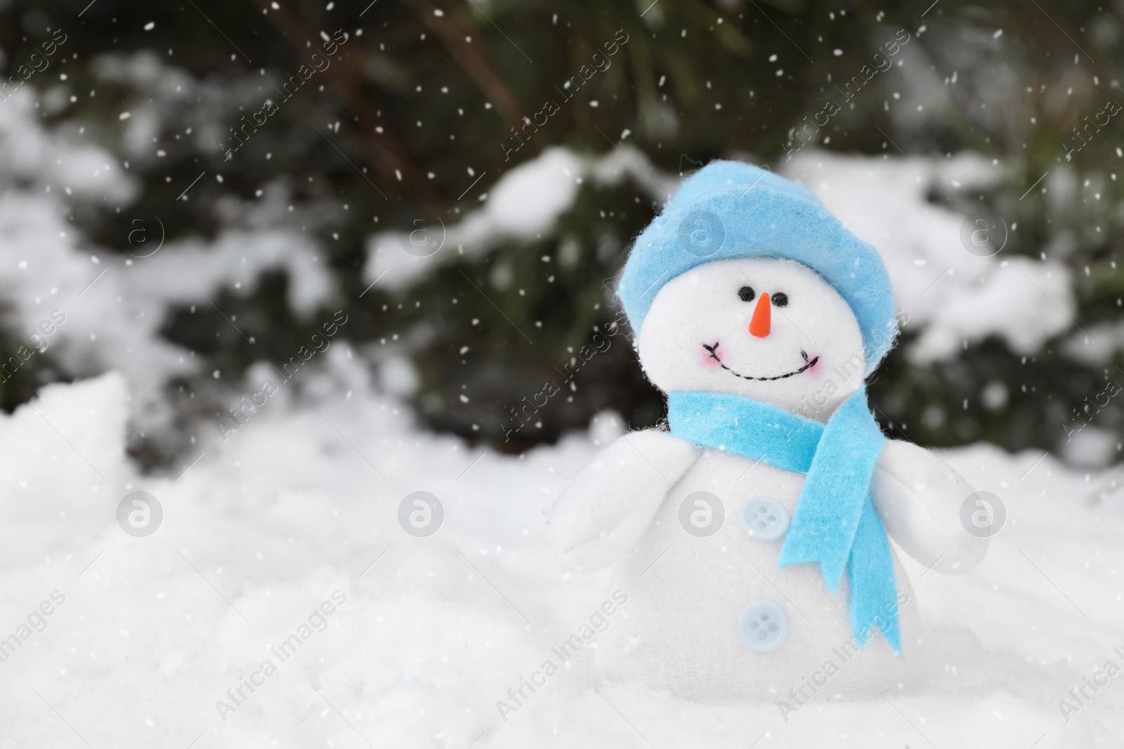 Photo of Cute small snowman toy on snow outdoors, space for text
