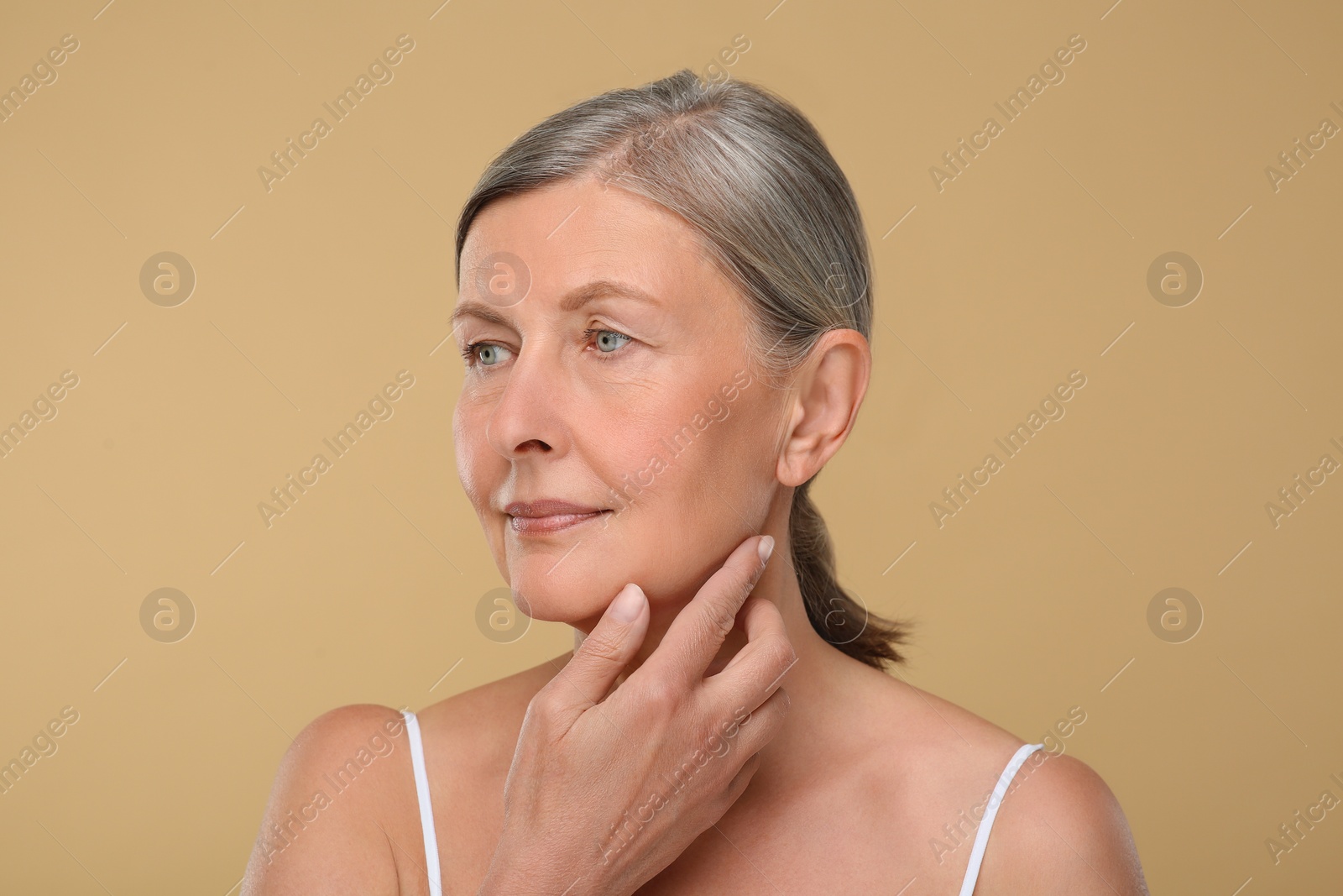 Photo of Portrait of senior woman with aging skin on beige background. Rejuvenation treatment