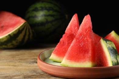 Photo of Plate with slices of juicy watermelon on wooden table, closeup. Space for text