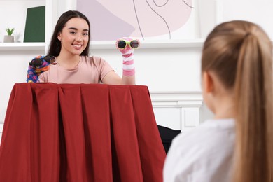 Happy mother performing puppet show for her daughter at home