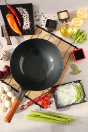 Photo of Wok, chopsticks and different products on white wooden table, flat lay