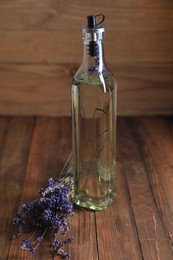 Photo of Bottle of cooking oil and lavender flowers on wooden table