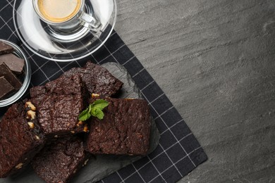 Photo of Delicious chocolate brownies with nuts and coffee on black table, flat lay. Space for text
