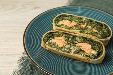 Pieces of delicious strudel with salmon and spinach on white wooden table, closeup