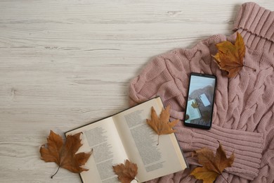 Photo of Flat lay composition with open book and autumn leaves on beige wooden table. Space for text