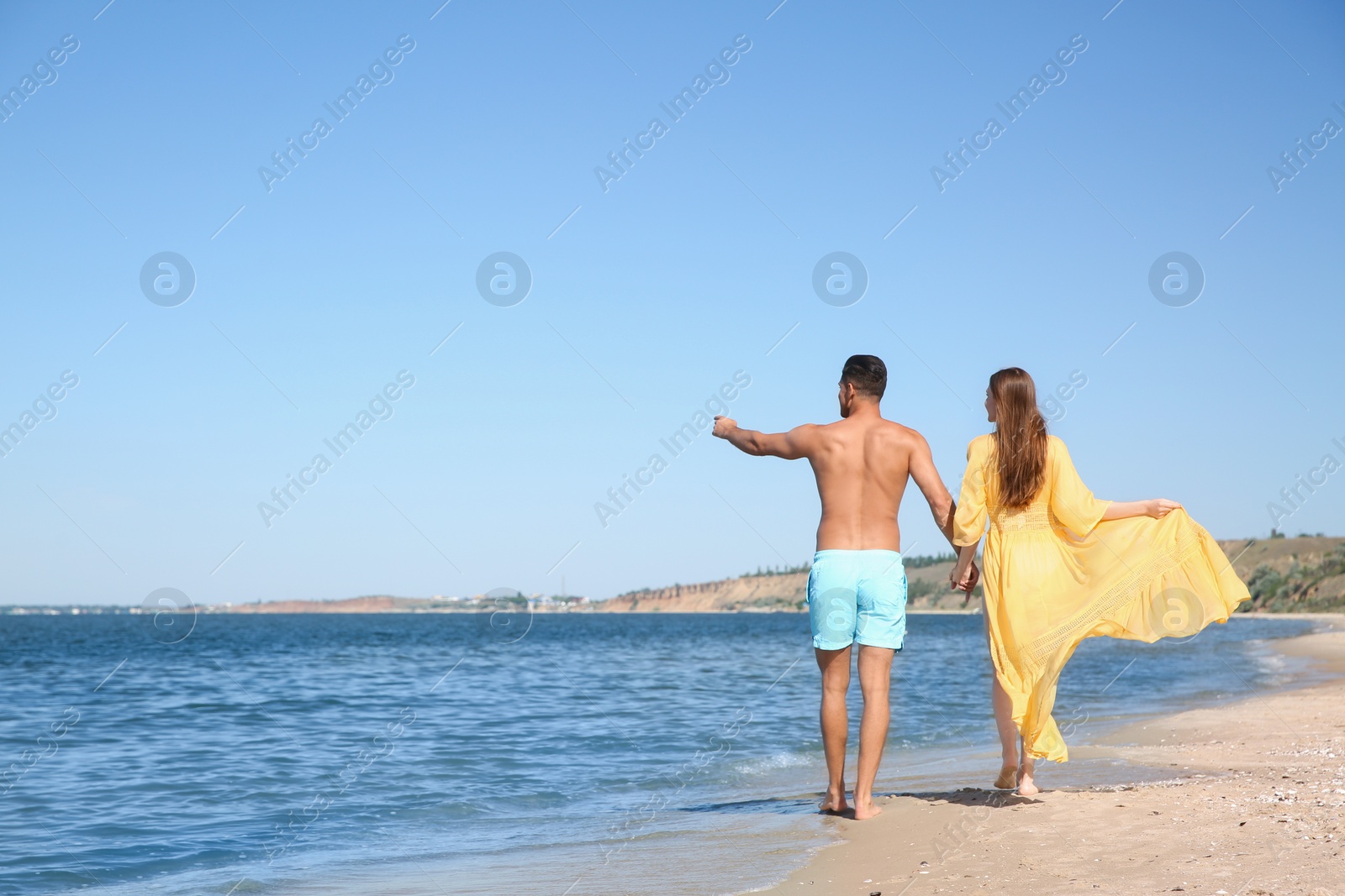 Photo of Woman in bikini and her boyfriend on beach, back view with space for text. Lovely couple