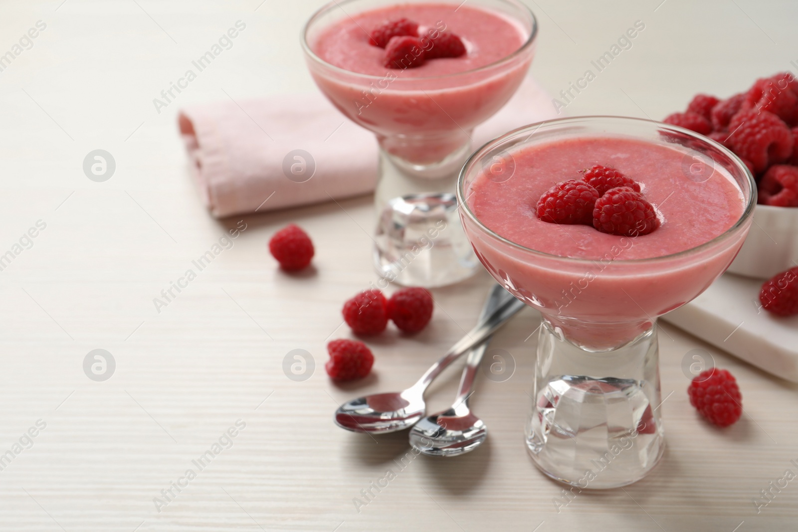 Photo of Delicious raspberry mousse on white wooden table, space for text