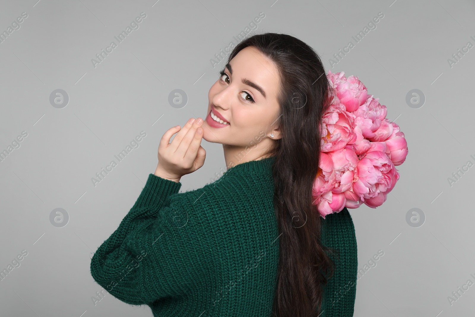 Photo of Beautiful young woman with bouquet of peonies on light grey background