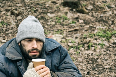 Photo of Poor homeless man with cup in city park