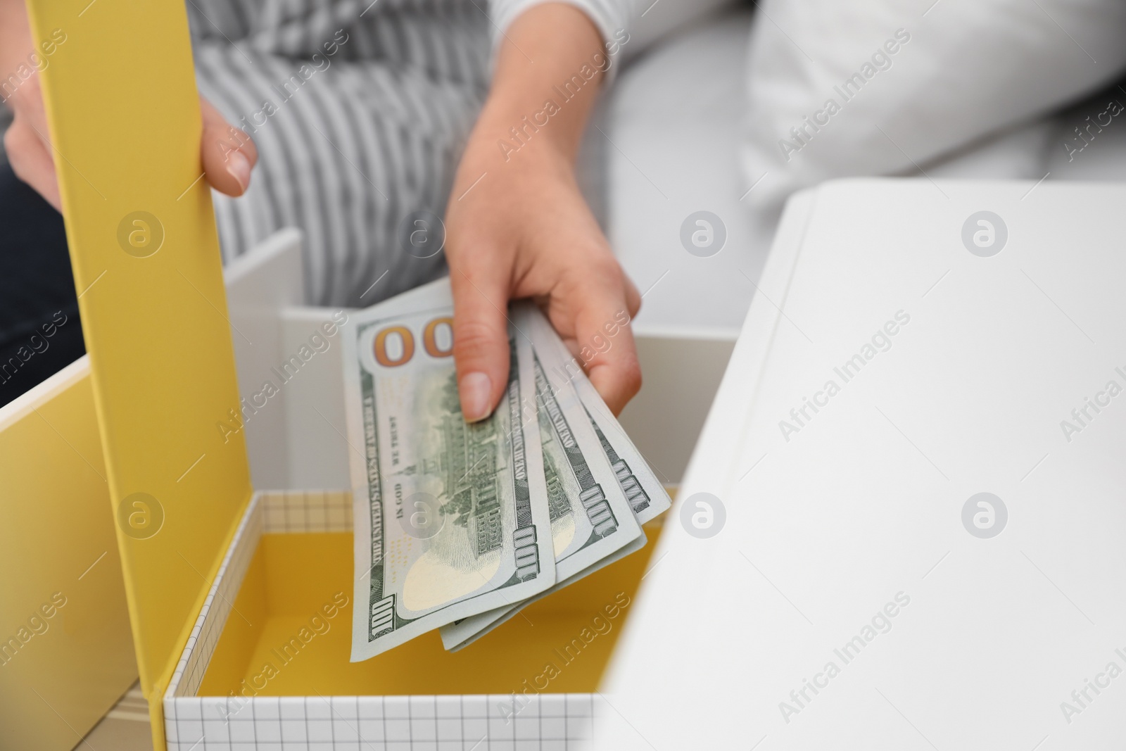 Photo of Woman hiding dollar banknotes in box at home, closeup. Money savings