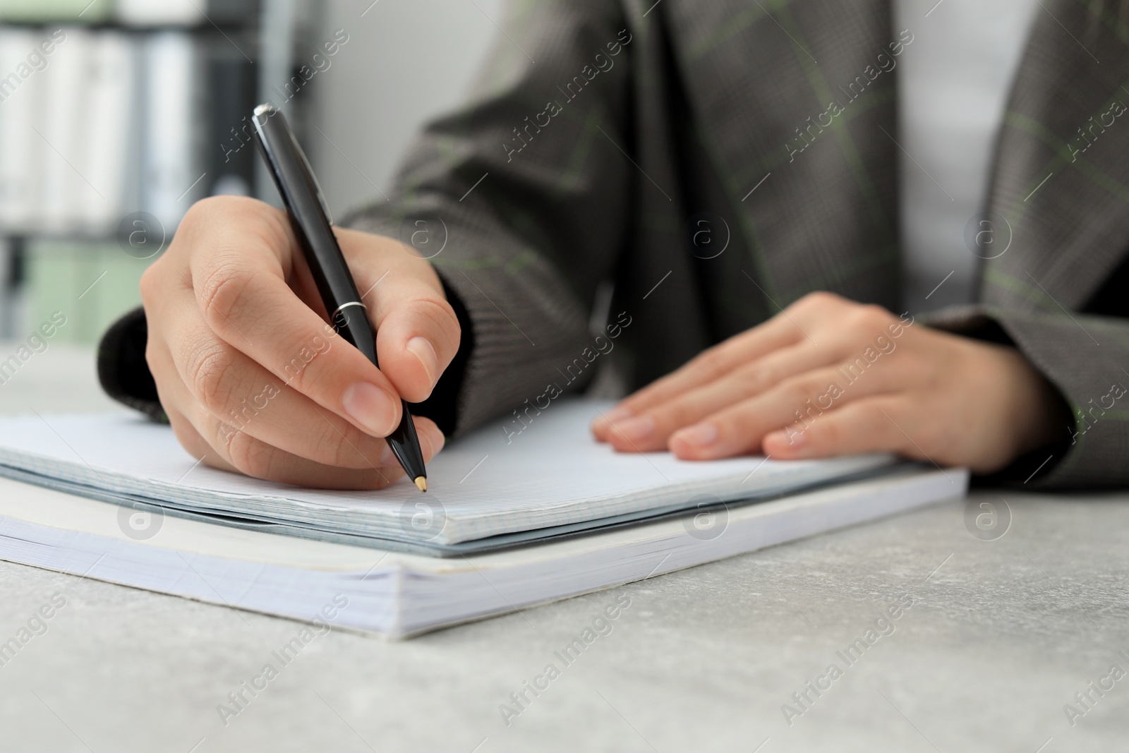 Photo of Woman writing in notebook at table indoors, closeup