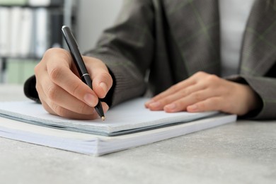 Photo of Woman writing in notebook at table indoors, closeup