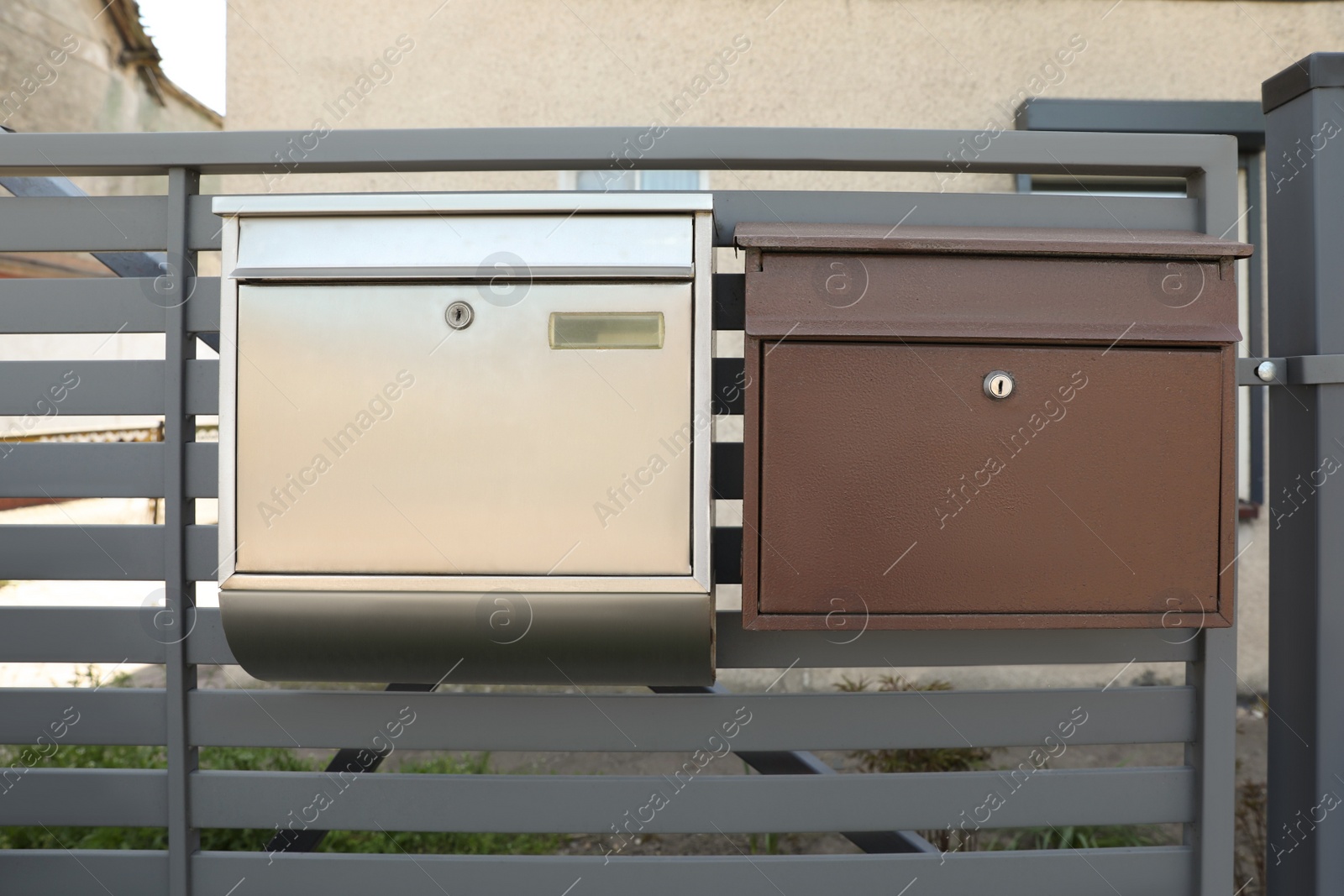 Photo of Different metal letter boxes on fence outdoors