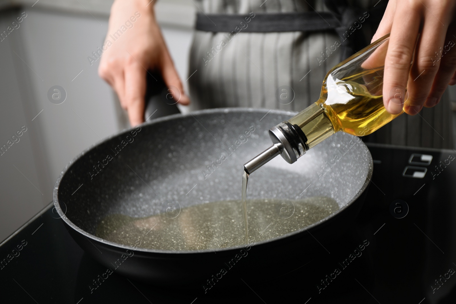 Photo of Woman pouring cooking oil from bottle into frying pan, closeup