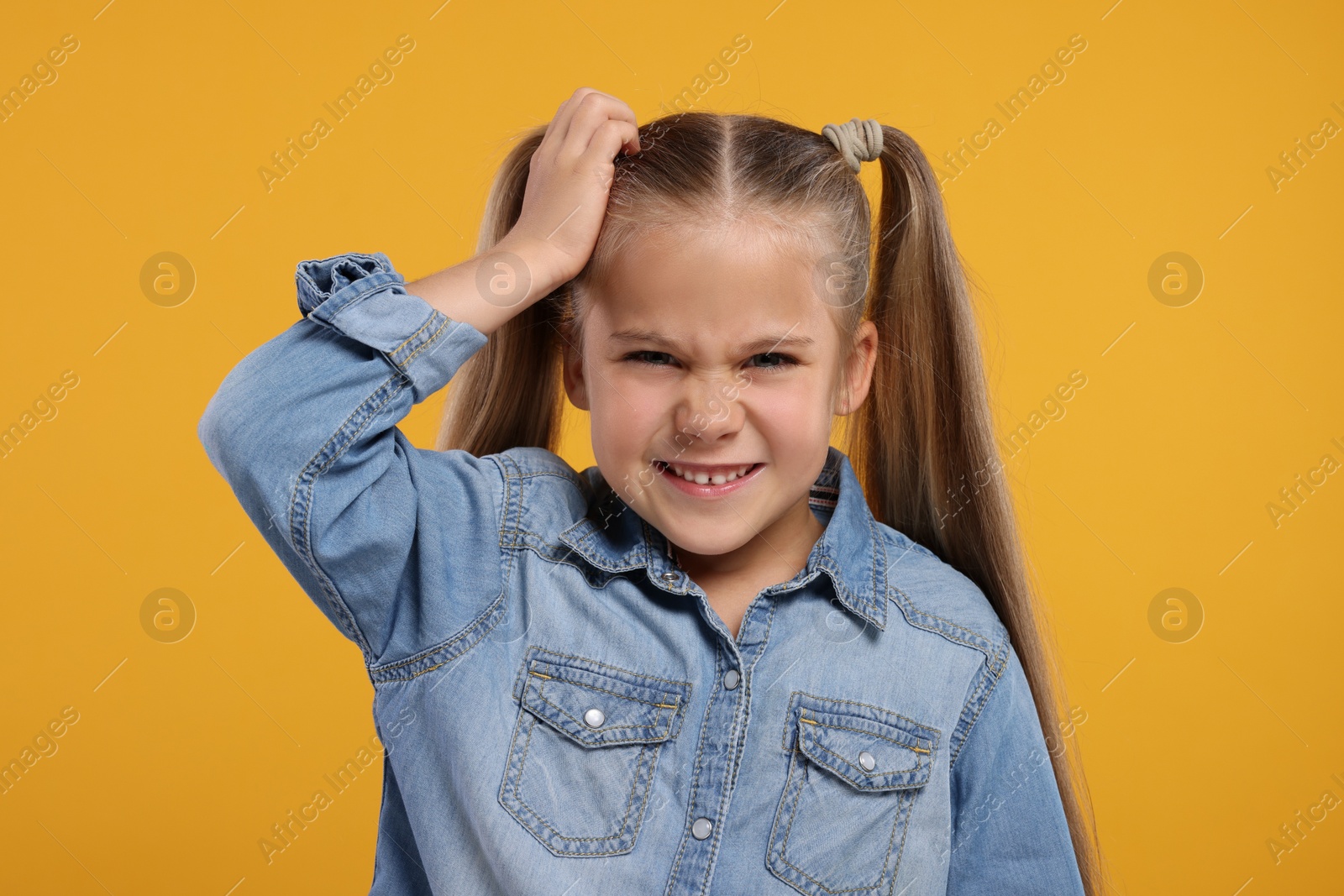 Photo of Portrait of embarrassed little girl on orange background