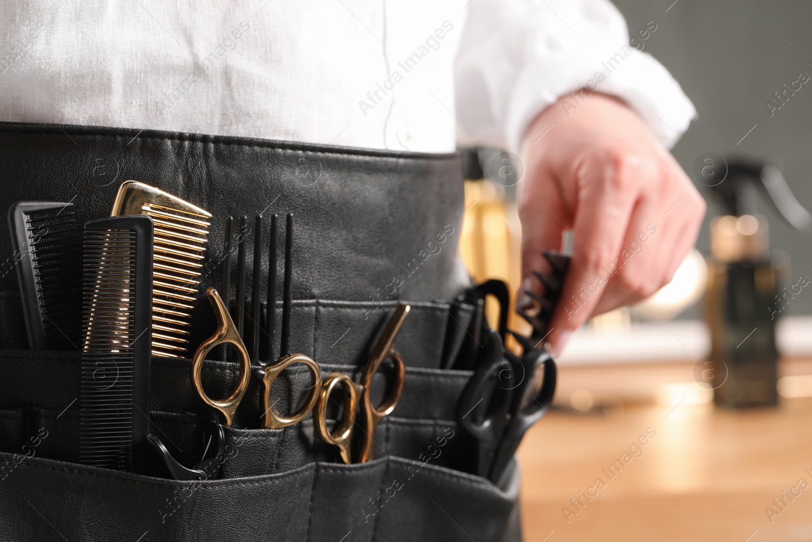 Photo of Hairstylist with professional tools in waist pouch in salon, closeup