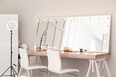 Photo of Modern mirror with light bulbs on dressing table in makeup room