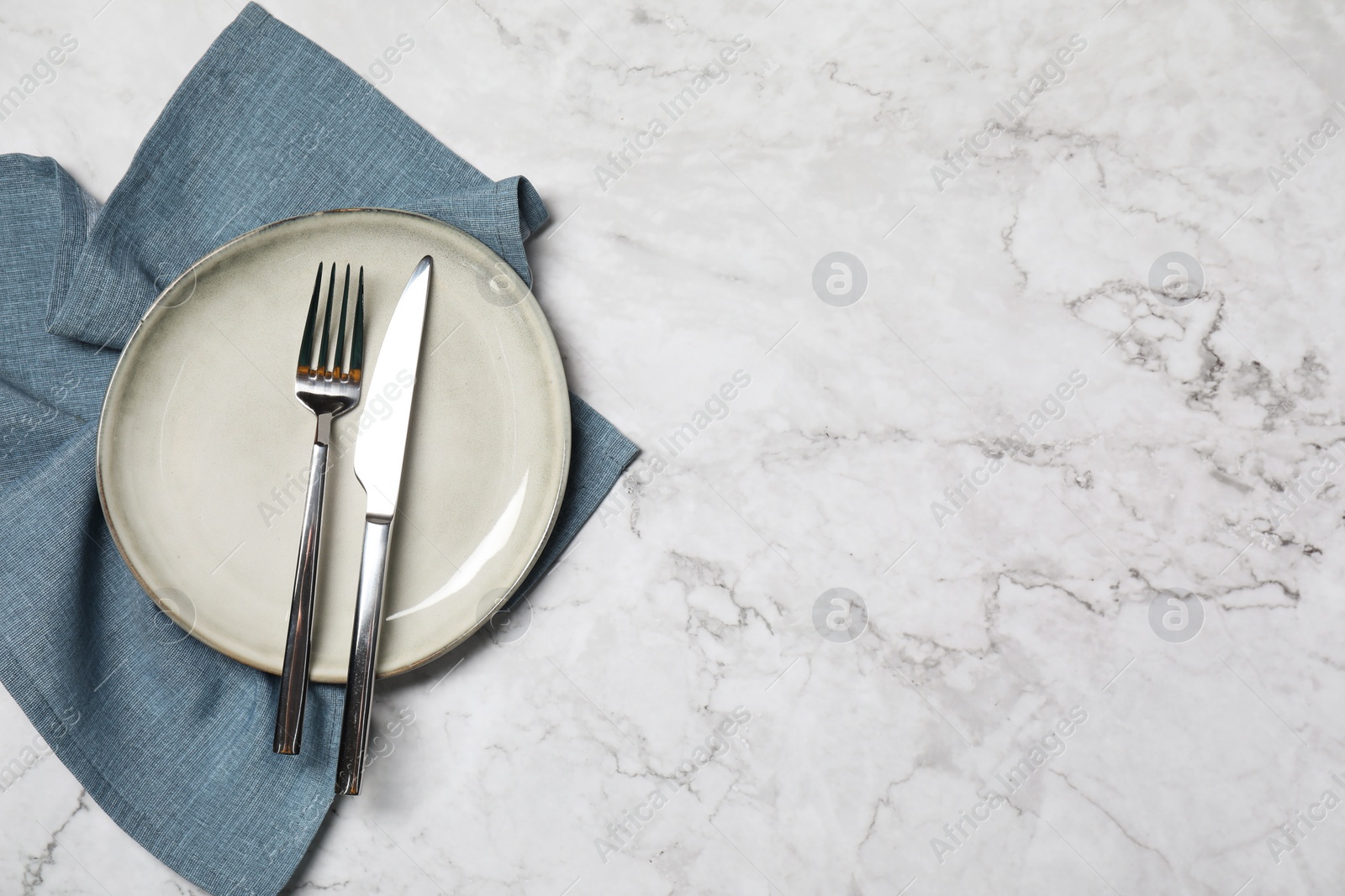 Photo of Stylish setting with elegant cutlery on white marble table, top view. Space for text