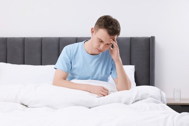 Photo of Sad man suffering from headache in bed indoors