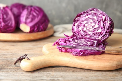 Photo of Fresh red cabbage, knife and cutting board on kitchen table