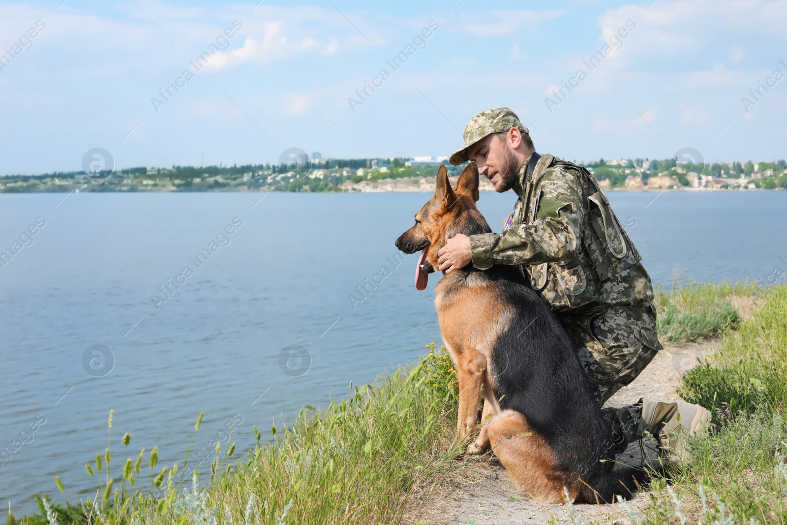 Photo of Man in military uniform with German shepherd dog outdoors