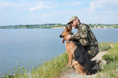 Photo of Man in military uniform with German shepherd dog outdoors