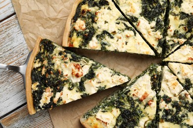 Taking piece of delicious homemade spinach quiche on rustic wooden table, flat lay