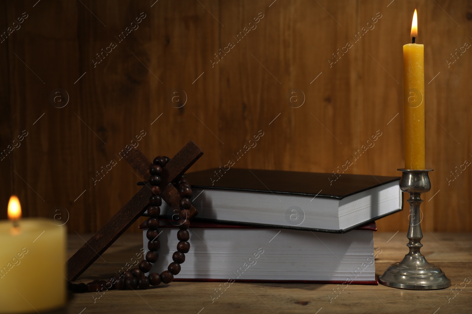 Photo of Church candles, Bible, cross and rosary beads on wooden table