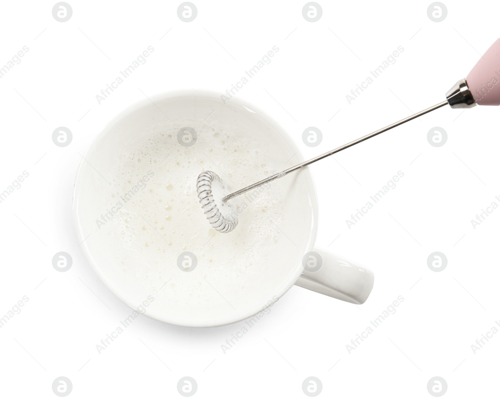 Photo of Whisking milk in cup with mini mixer (frother wand) isolated on white, top view