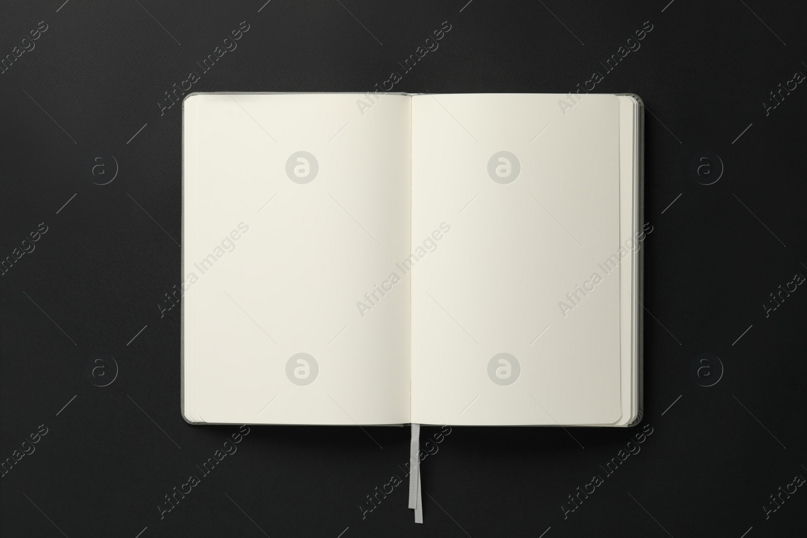 Photo of Open blank notebook on black background, top view