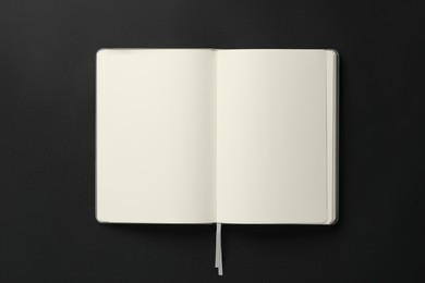 Photo of Open blank notebook on black background, top view