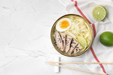 Bowl of delicious rice noodle soup with meat and egg on white textured table, flat lay. Space for text