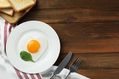 Photo of Romantic breakfast with heart shaped fried egg served on wooden table, flat lay. Space for text