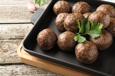 Photo of Tasty cooked meatballs with parsley on wooden table, closeup