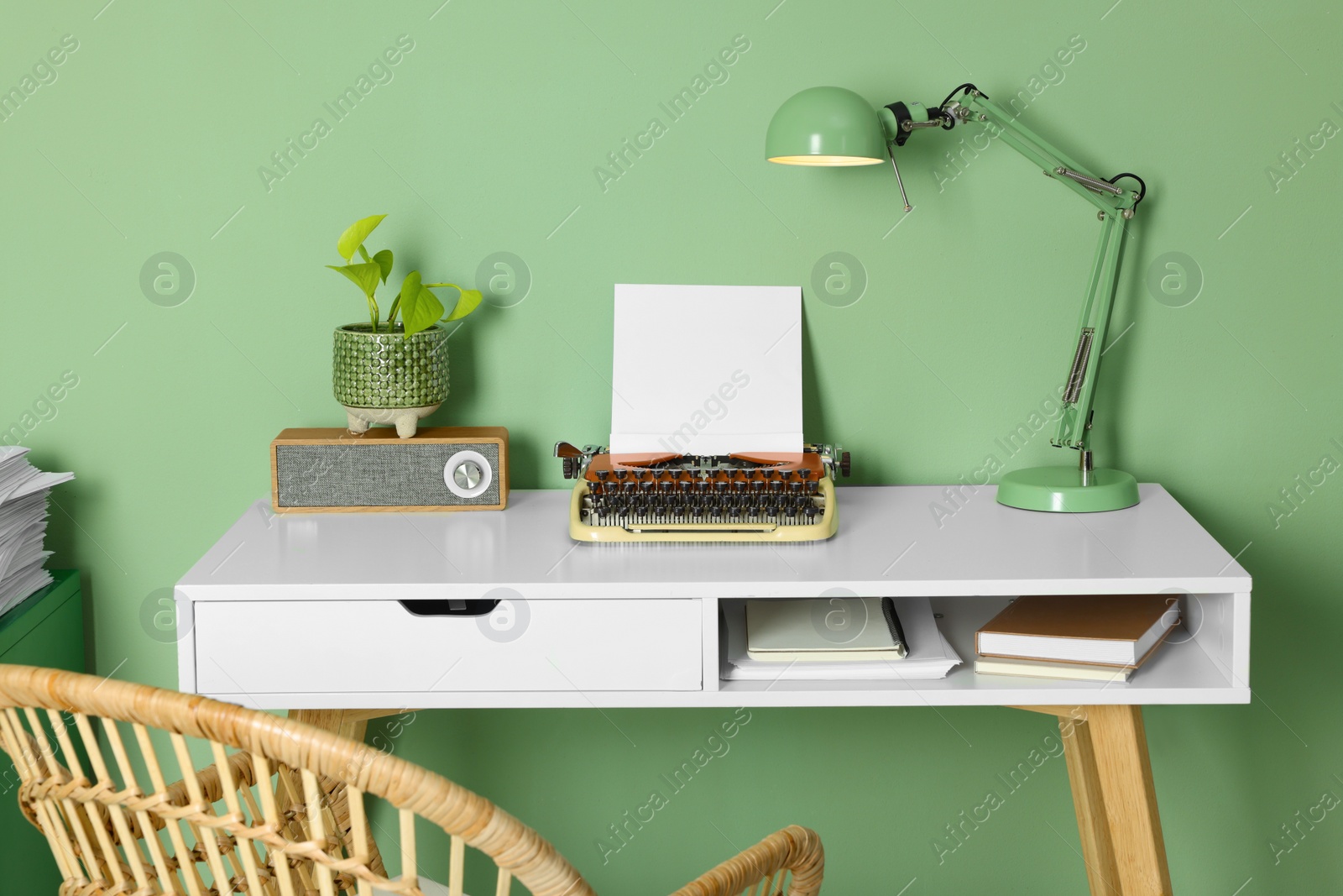 Photo of Writer's workplace with typewriter on wooden desk near pale green wall in room