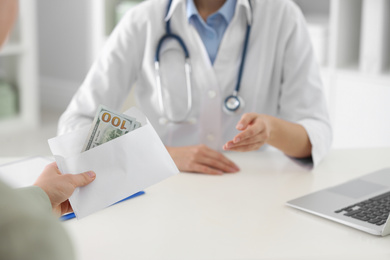 Patient giving bribe to doctor in clinic, closeup. Corrupted medicine