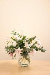 Bouquet of beautiful lily flowers in vase on wooden table against beige background, space for text