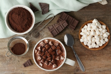 Composition with delicious hot cocoa drink and marshmallows on wooden background, flat lay