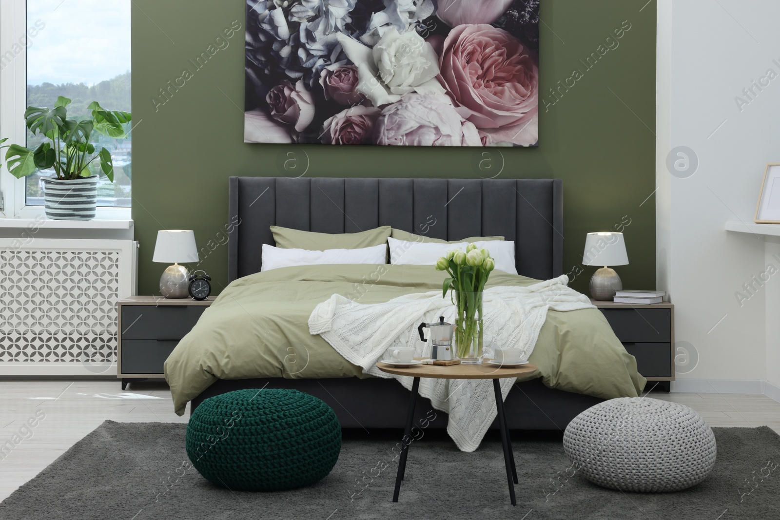 Photo of Stylish bedroom with comfortable bed, bedside tables and vase of tulips. Interior design