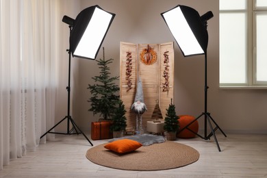 Photo of Beautiful Christmas themed photo zone with professional equipment, trees and dwarf in room