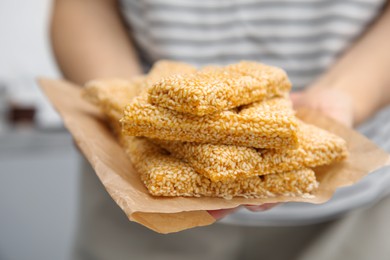 Photo of Woman holding delicious sesame kozinaki bars, closeup