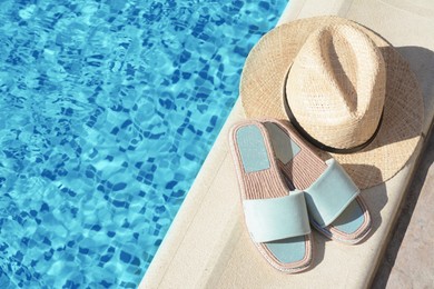 Stylish slippers and straw hat at poolside on sunny day, space for text. Beach accessories