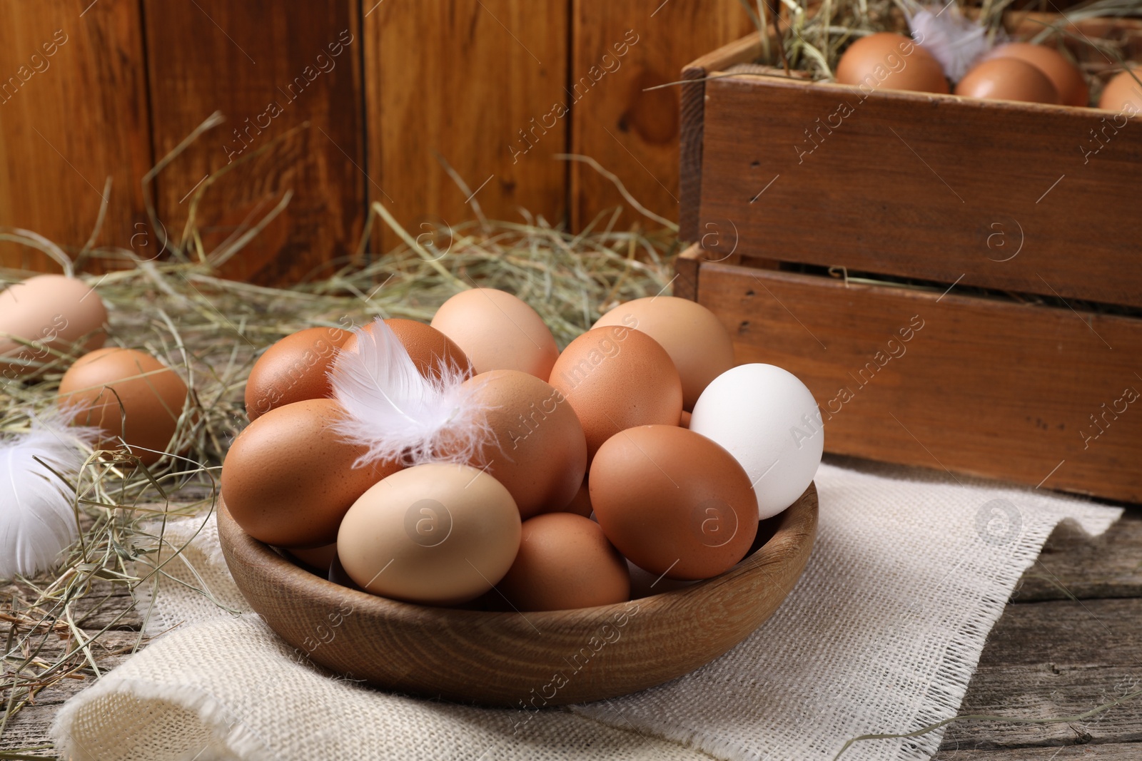 Photo of Fresh chicken eggs and dried hay on wooden table