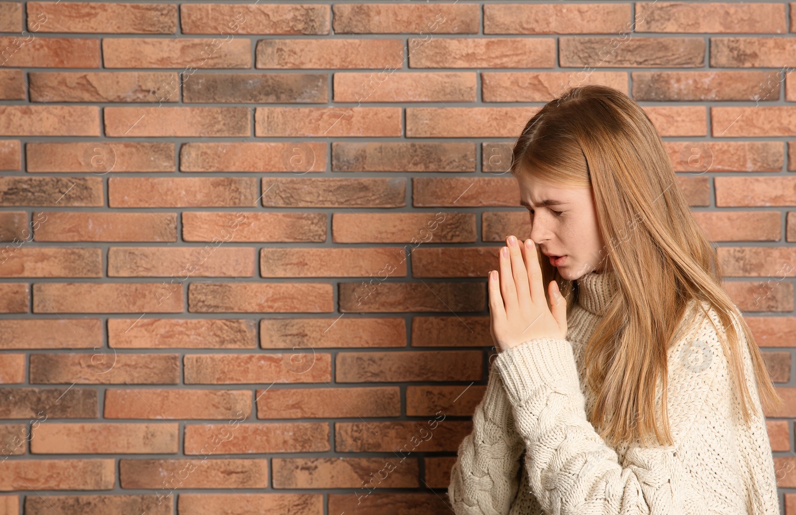 Photo of Teenage girl suffering from cough near brick wall. Space for text